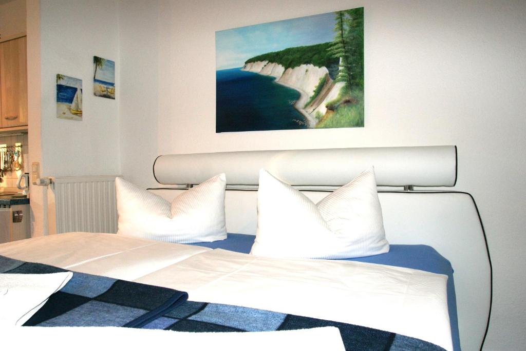 Una cama con almohadas blancas y una pintura encima. en Studio 22 Residenz Seeblick, en Ostseebad Sellin