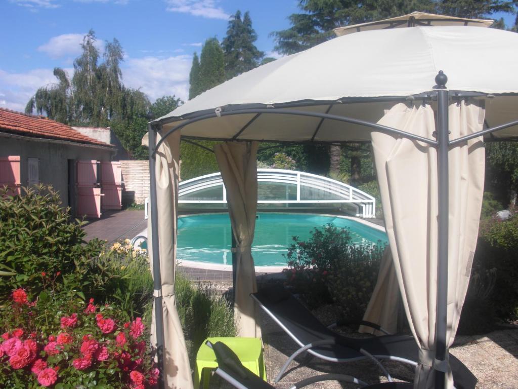 biały parasol na dziedzińcu z basenem w obiekcie Le Clos Sainte Lea w mieście Mouilleron-le-Captif