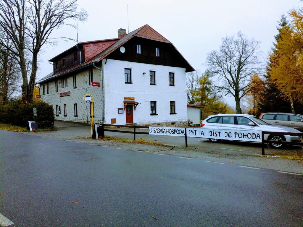 ein weißes Haus mit einem Schild davor in der Unterkunft Penzion Vozzýk in Nové Hutě