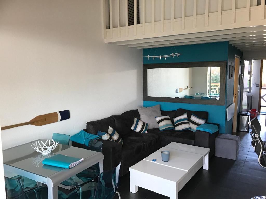 sala de estar con sofá negro y mesas en residence neptune beach, en Andernos-les-Bains