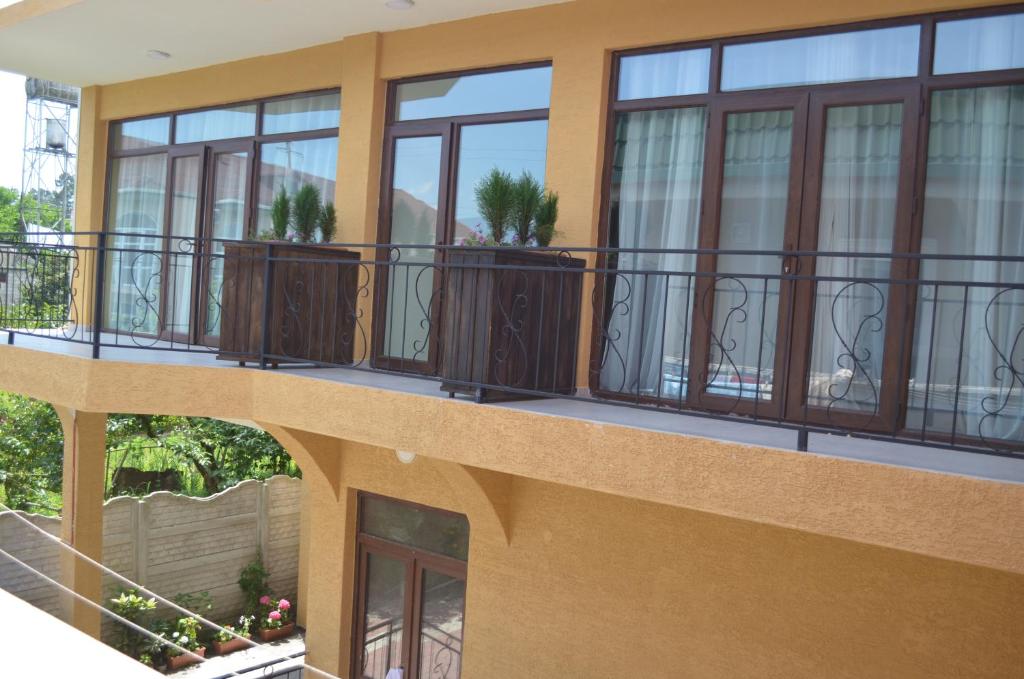 einen Balkon eines Gebäudes mit Fenstern und Pflanzen in der Unterkunft Guest House Madonna in Kobuleti
