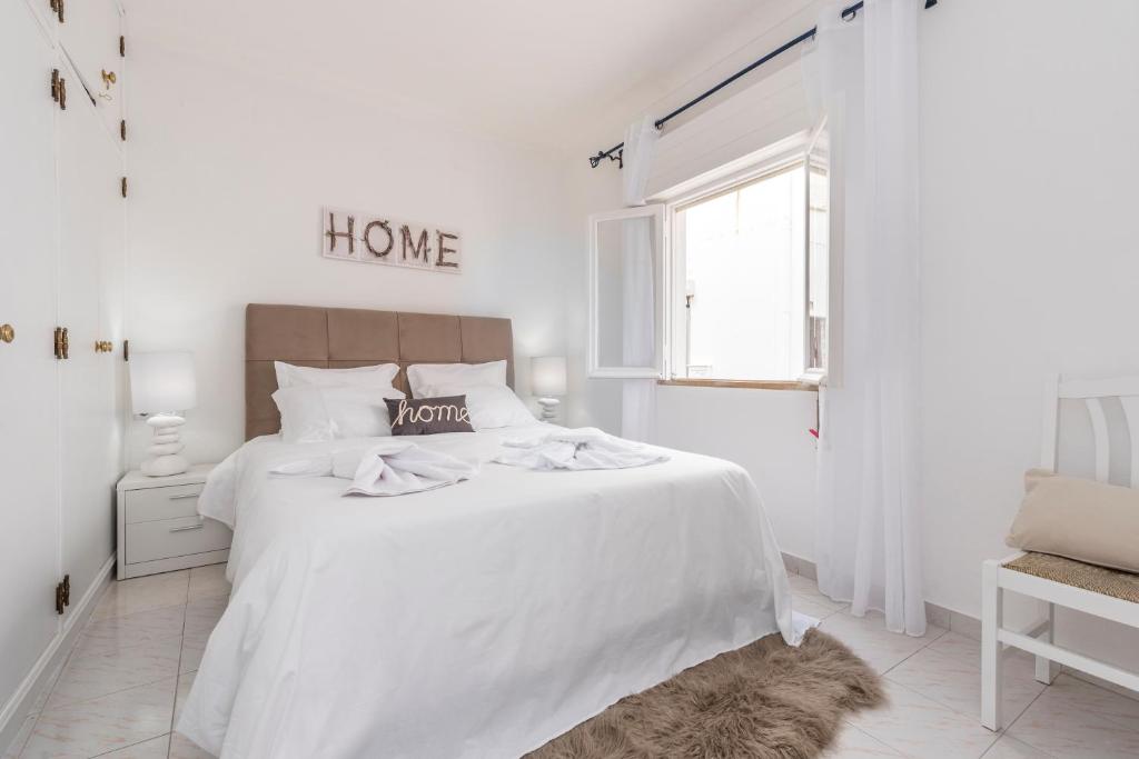 ein weißes Schlafzimmer mit einem weißen Bett und einem Fenster in der Unterkunft Fisherman's Beach Home 2BR 2BA AC Wi-Fi in Albufeira