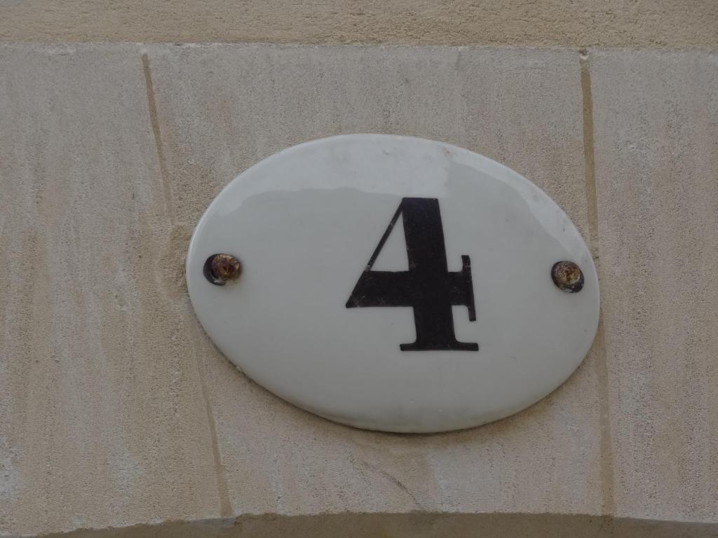 Biała płyta z numerem cztery na ścianie w obiekcie Le 4 w mieście Bayeux