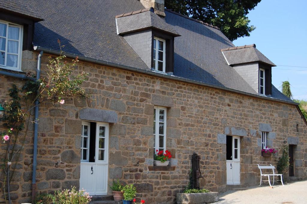 an old stone house with white doors and a roof at Le Pont St Michel in Les Portes du Coglais