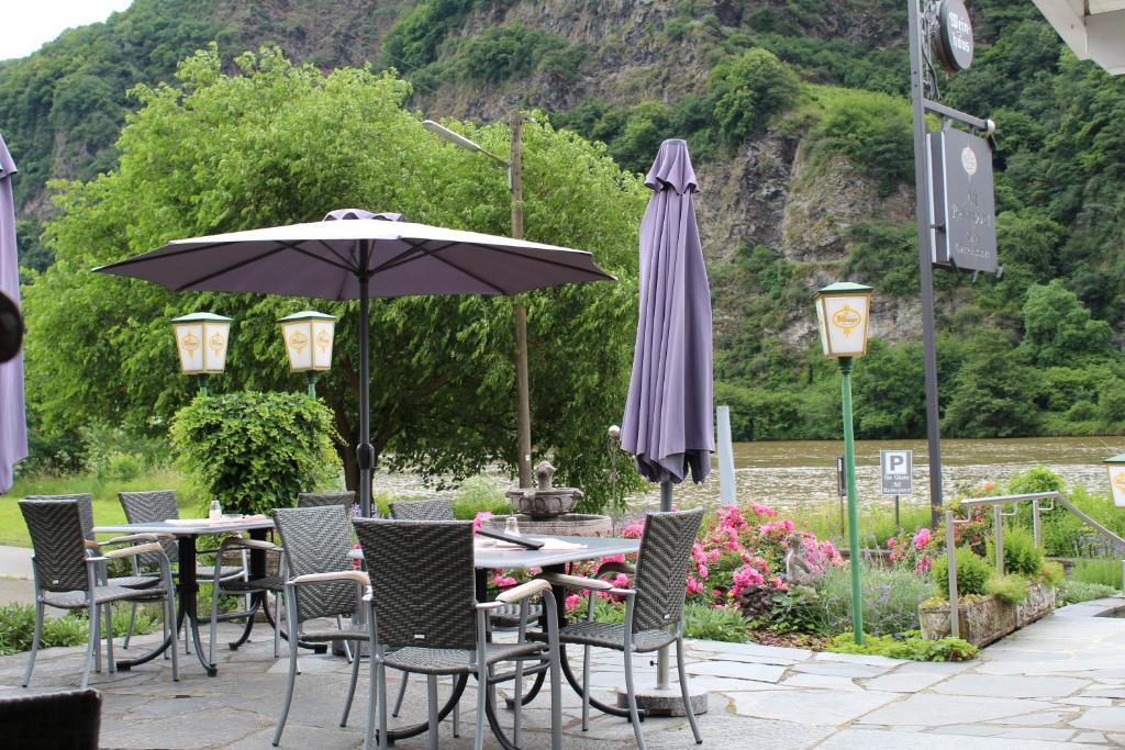 un patio con mesas, sillas y una sombrilla en Alt Reinsport en Piesport