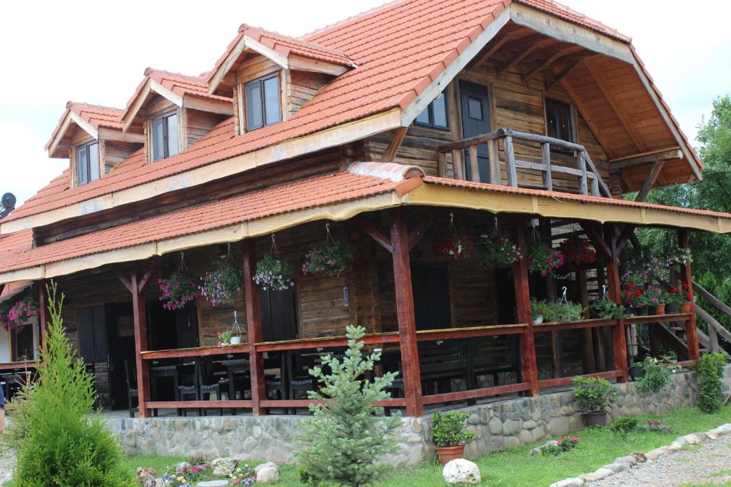 a large wooden house with a red roof at Satul Traditional in Runcu
