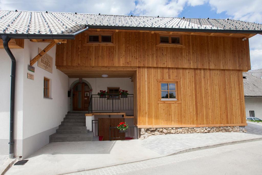 een groot houten gebouw met een veranda en een trap bij 1861 Blejka apartments Bled in Bled