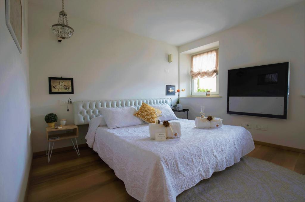 1 dormitorio con 1 cama blanca y TV de pantalla plana en In Casa, en Verona