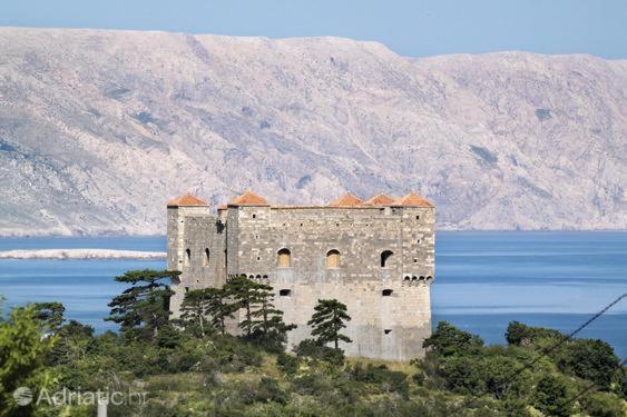 a castle on top of a hill next to a body of water at Guest House Iva in Senj