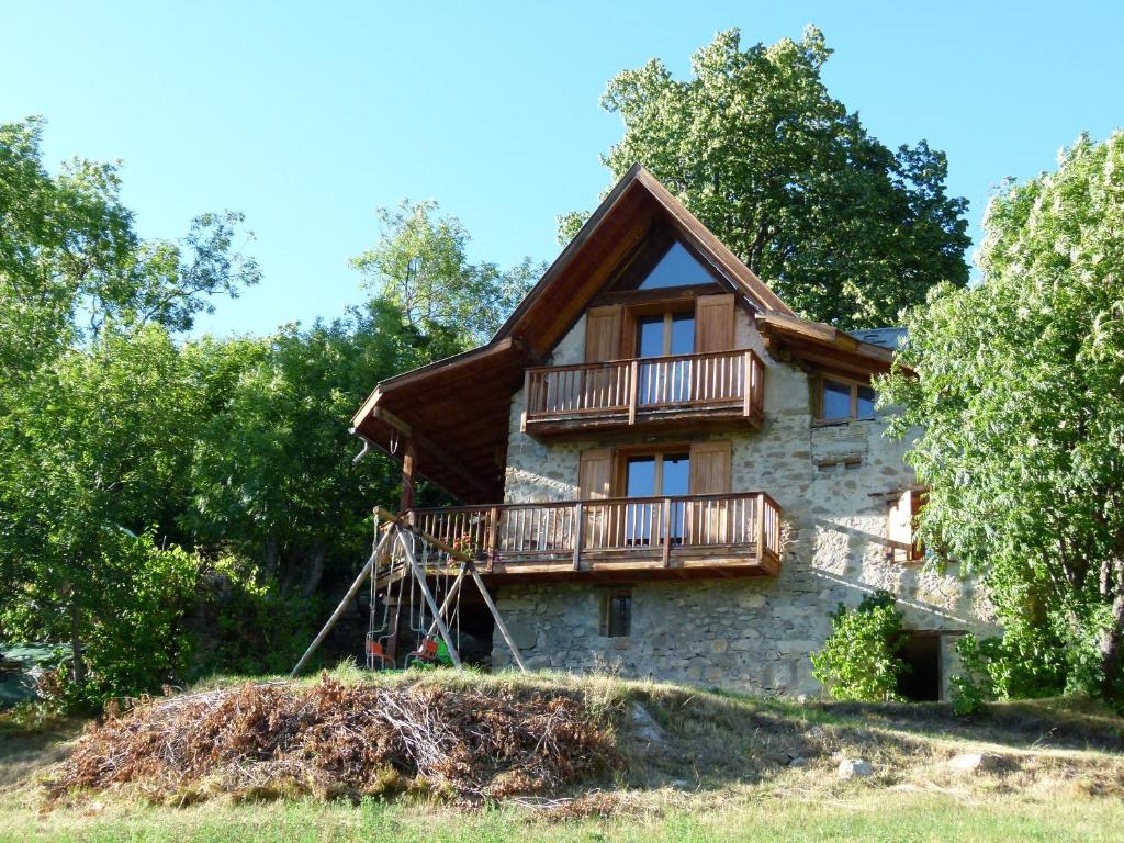 a stone house with a balcony and trees at Les Murets in Colmars