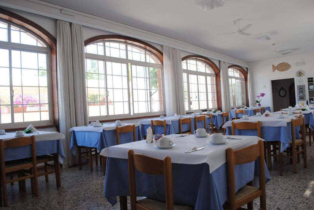 a dining room with tables and chairs and windows at Hotel Mastropeppe in San Felice Circeo