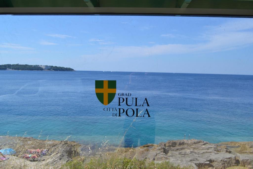 a view of the ocean from a window with the words pula oh pula at Apartments Nicole in Pula