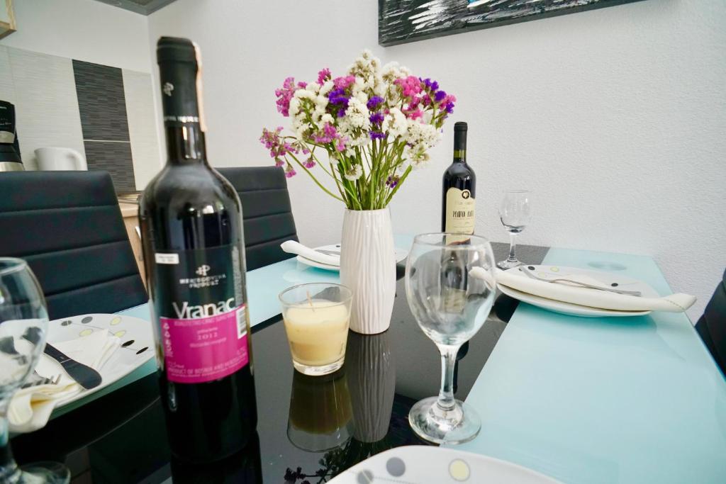 una mesa con dos botellas de vino y flores. en Apartments Bruna Trogir en Trogir