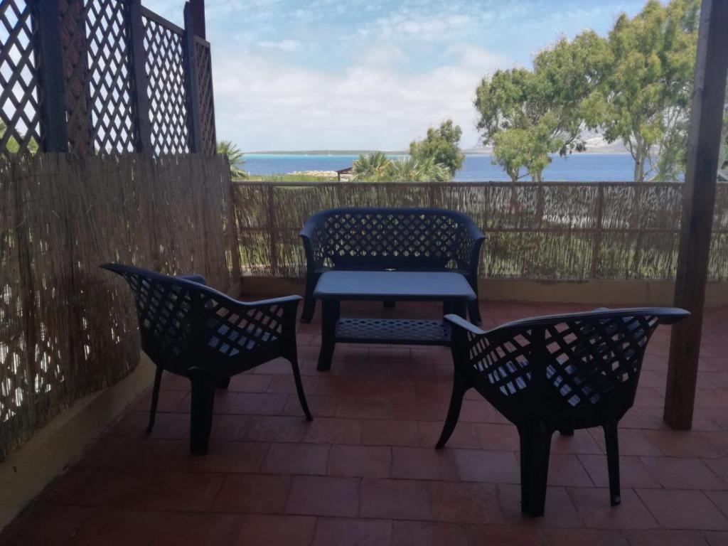 dwa krzesła i stół na patio z widokiem na ocean w obiekcie Mare Blu w mieście Stintino