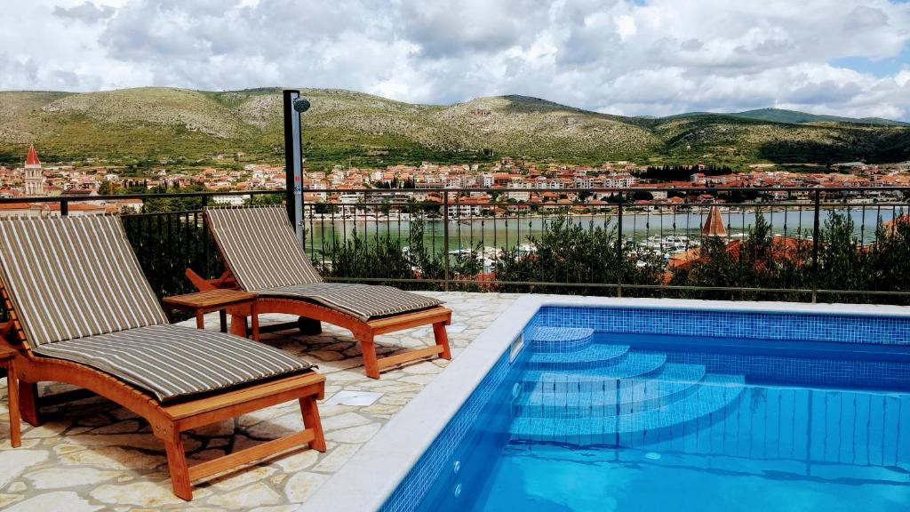 un patio con 2 sillas y una piscina en Apartmani Balan s vanjskim bazenom, en Trogir