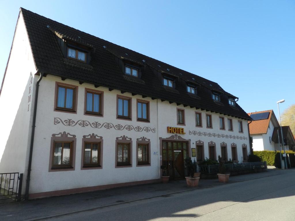 a white building with a black roof on a street at Hotel Garni KAMBEITZ in Ötigheim