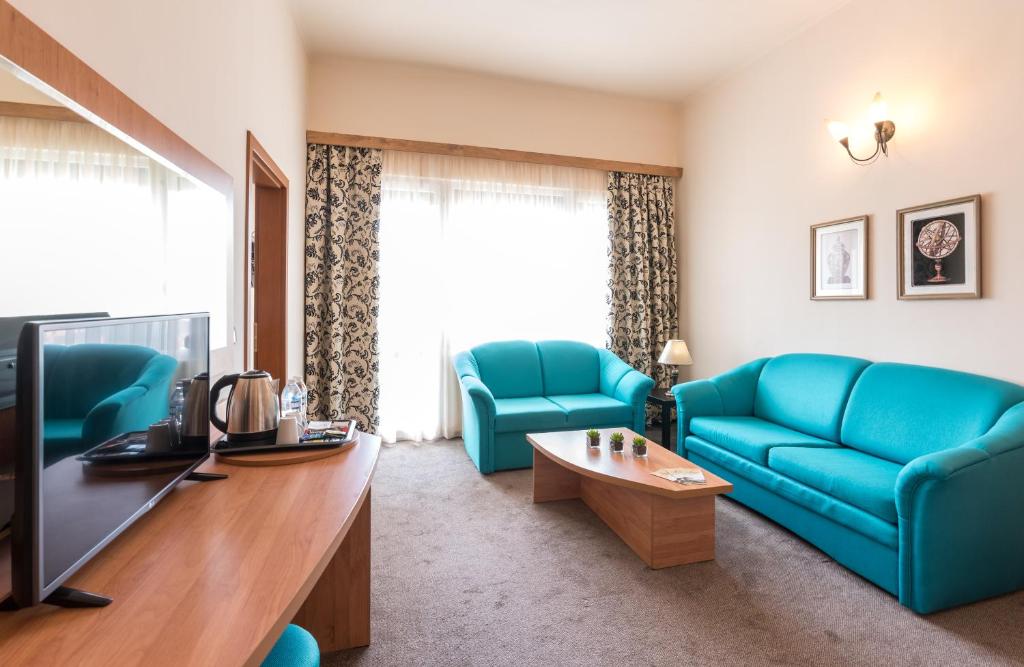 a living room with blue couches and a tv at Lotus Family Hotel - Free Parking in Sunny Beach