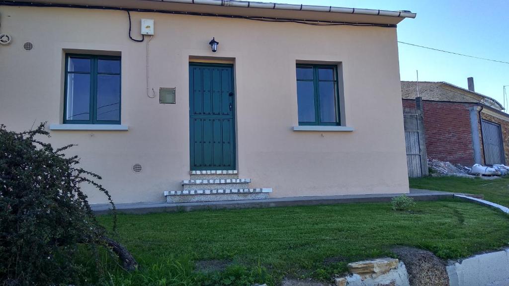 ein weißes Haus mit einer blauen Tür und einem Hof in der Unterkunft casa carballal in Lorenzana