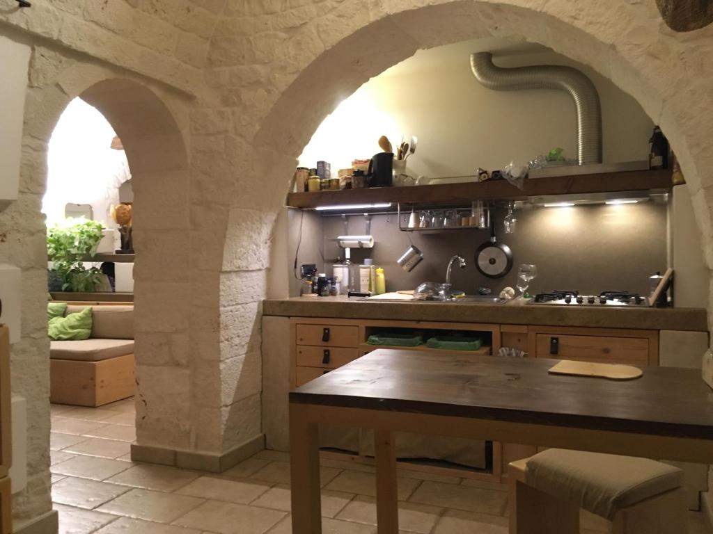 una cucina con arco in pietra e tavolo di B&B Via dei Trulli a Cisternino