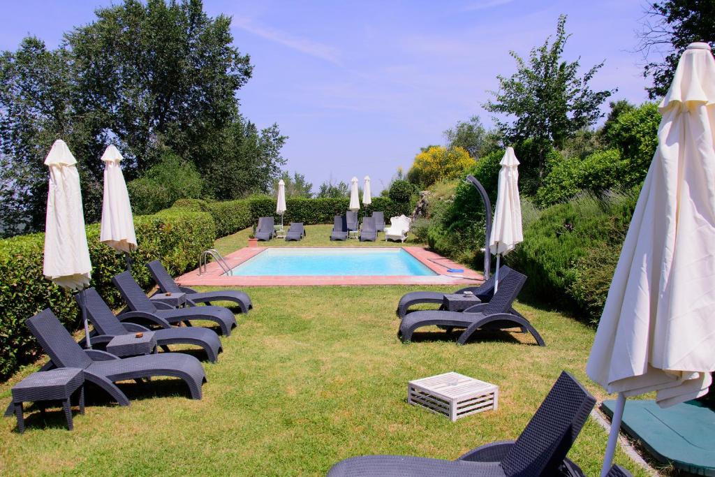 a group of chairs and umbrellas next to a pool at Residenzia Del Sogno in Castellina in Chianti