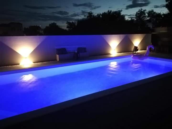 ein Pool in der Nacht mit blauer Beleuchtung in der Unterkunft Apartment D&D in Bibinje