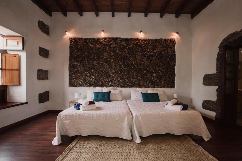 
a large white bed sitting in front of a large window at Hotelito Rural Flor de Timanfaya in Tinajo

