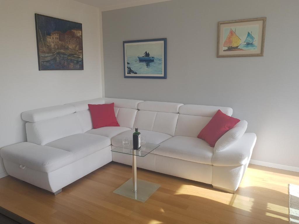 a living room with a white couch and red pillows at Apartment Maris in Omiš
