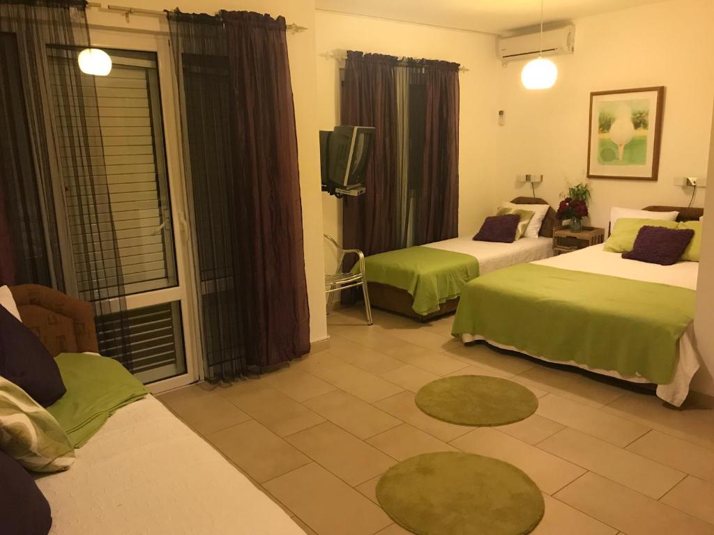 a hotel room with two beds and a television at Guest House Villa Alea in Dobra Voda