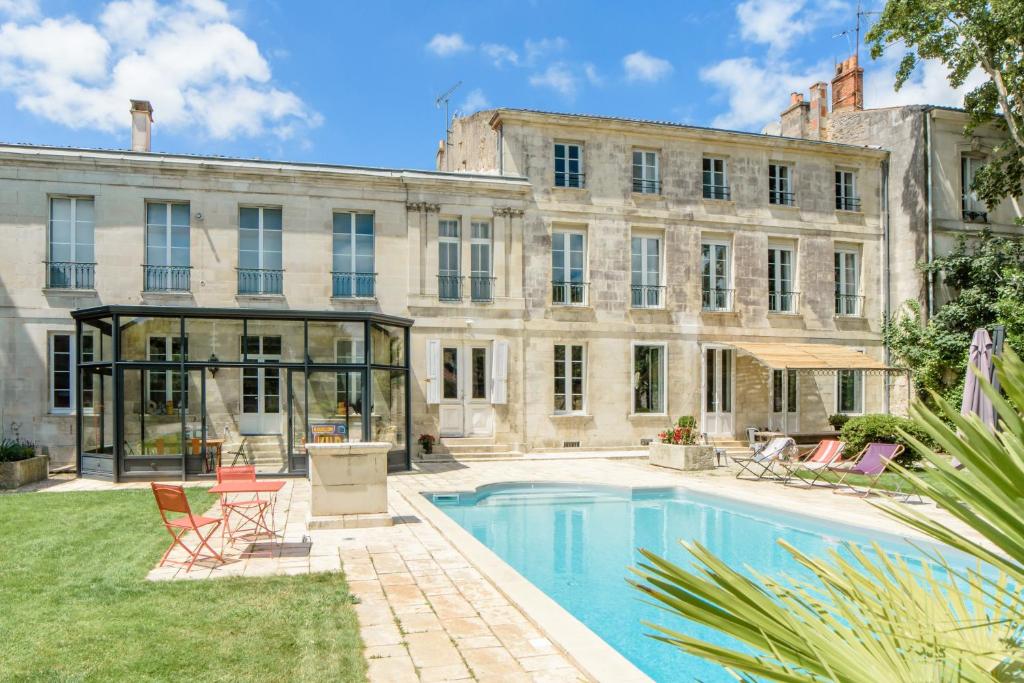 
a large building with a pool and lawn chairs in front of it at L'esprit du 8 in Rochefort
