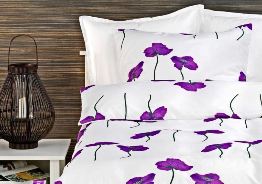 a bed with purple flowers on it at Apartamenty Centrum in Szczecin