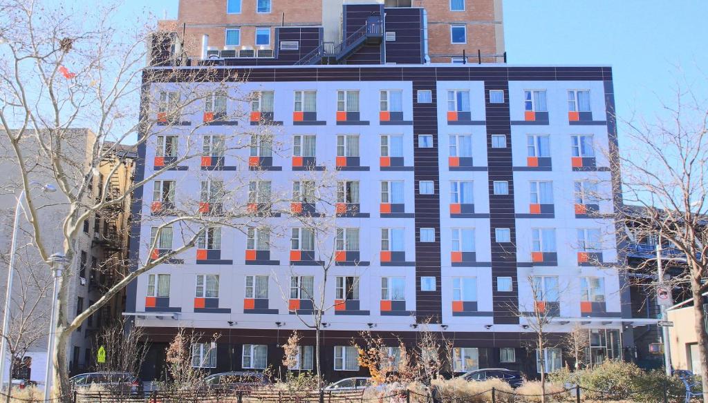 a tall white building with orange and black windows at Madison LES Hotel in New York