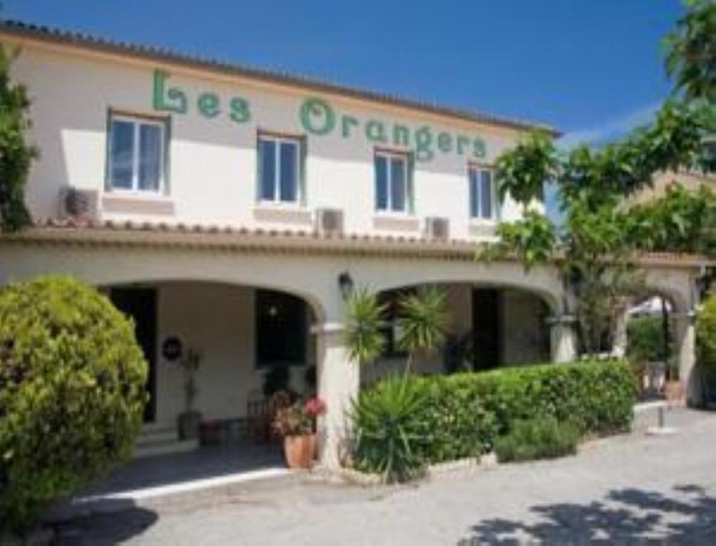 a white building with a sign that reads less orange at Les Orangers in Aléria