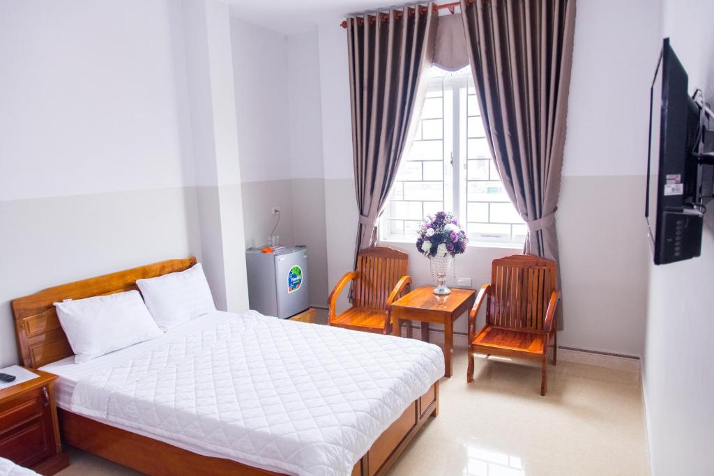 a bedroom with a bed and two chairs and a window at Hoang Thinh Hotel in Kon Tum (2)