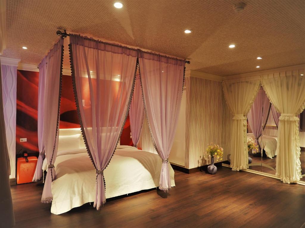 1 dormitorio con 1 cama con cortinas moradas en Day Chen Hotel, en Yilan City