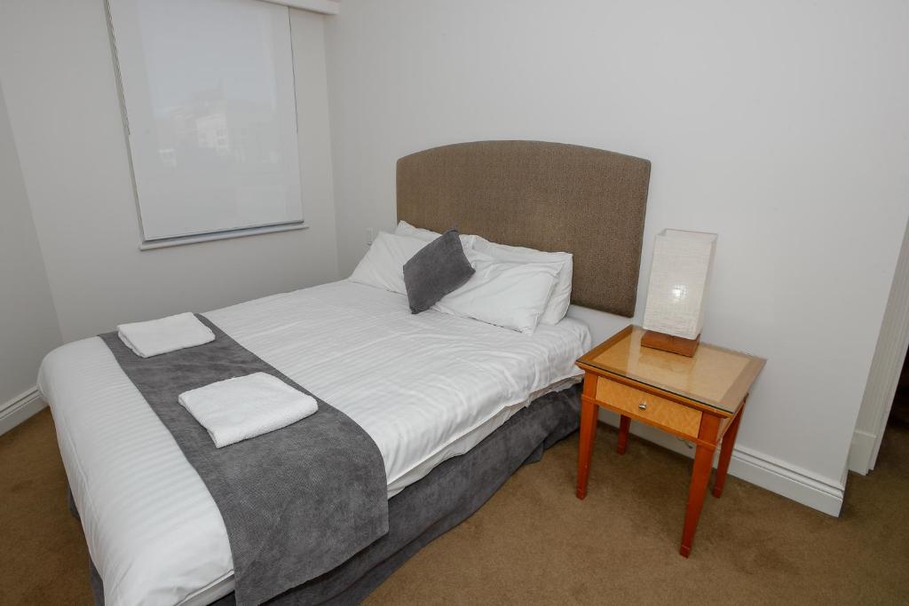 a small bedroom with a bed and a table at Bond 1603 Self Catering in Sydney
