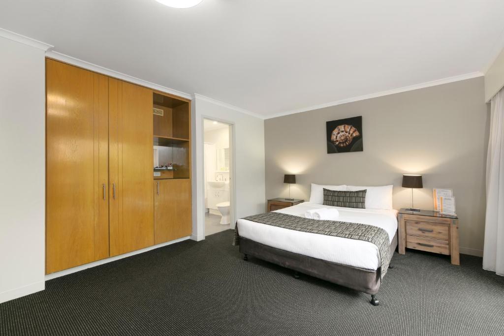 1 dormitorio con 1 cama y armario de madera en Mt Ommaney Hotel Apartments, en Brisbane