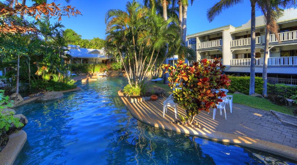 - une piscine dans un complexe avec des chaises et des fleurs dans l'établissement Sovereign Resort Hotel, à Cooktown