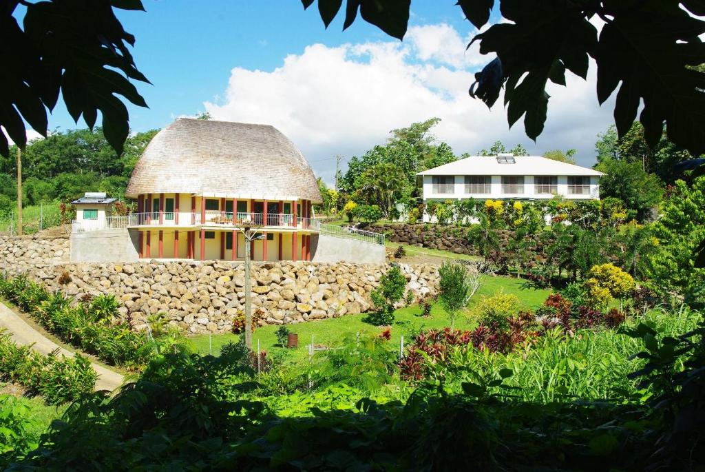 a house with a thatched roof and a garden at Samoan Highland Hideaway in Siusega