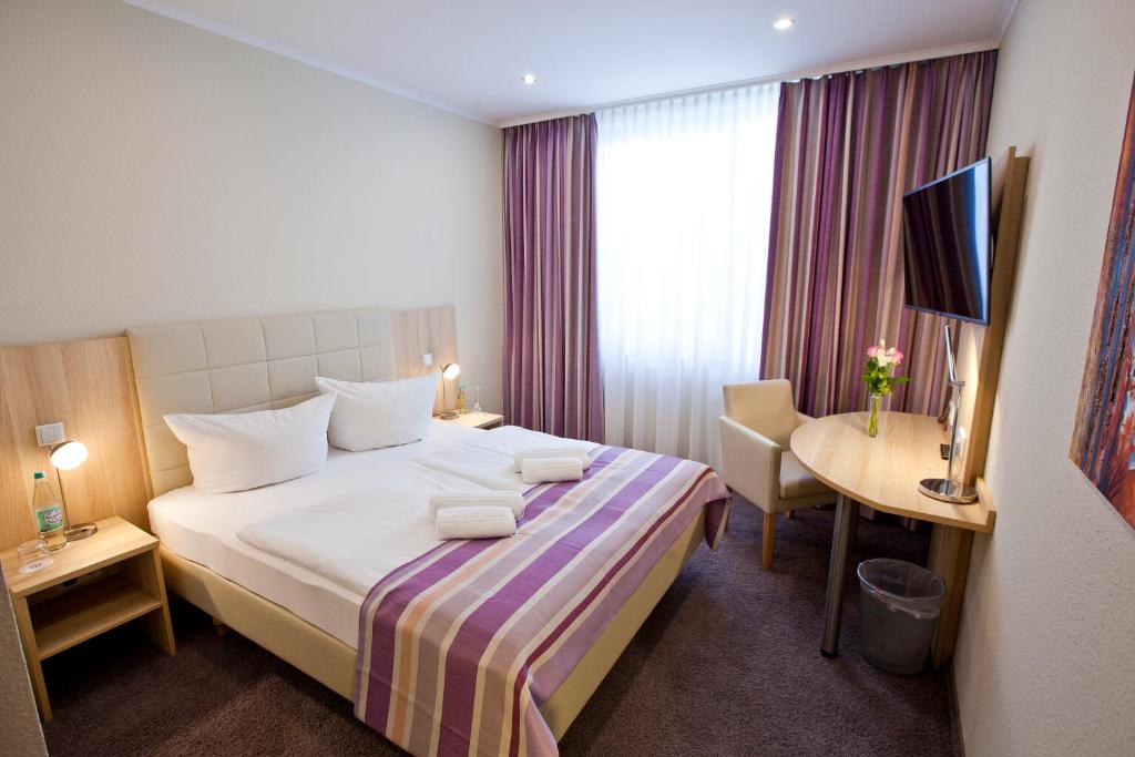 ein Hotelzimmer mit einem großen Bett und einem Schreibtisch in der Unterkunft Hotel Siebenschläfer in Alsdorf