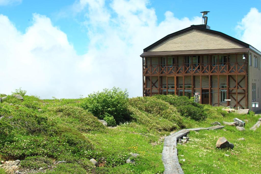 a building on a hill with a cross on top at Tengudaira Mountain Lodge in Tateyama