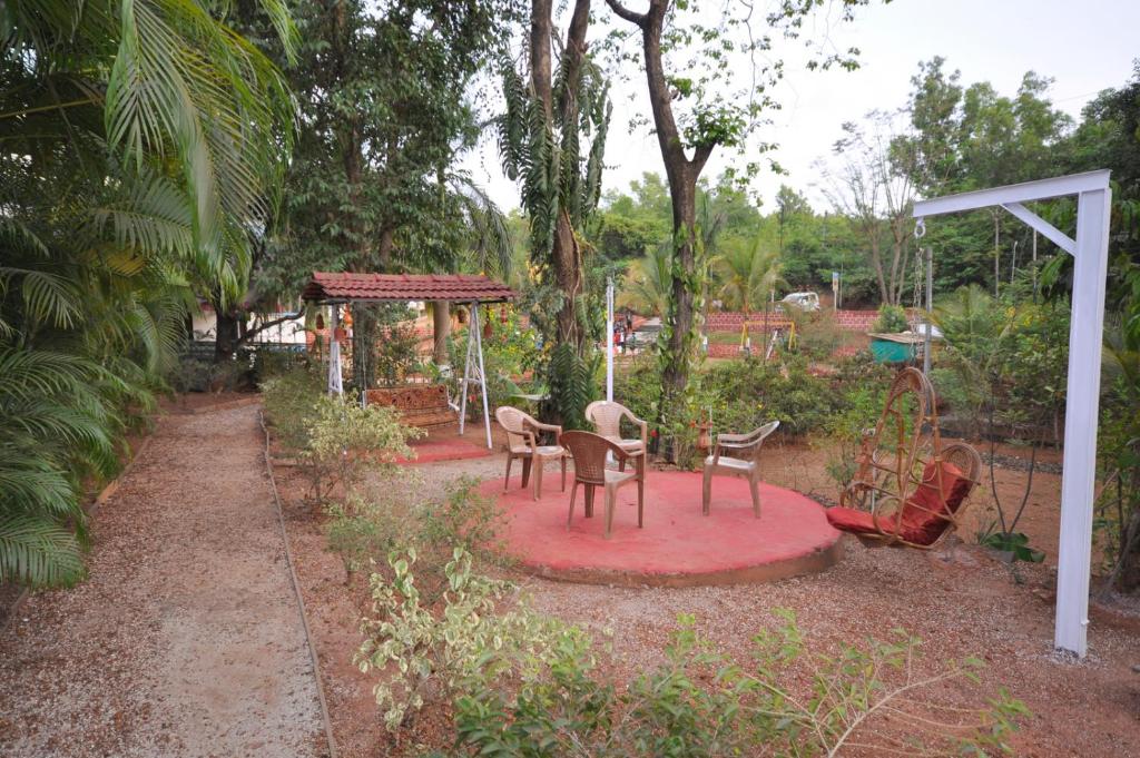 um pátio com cadeiras, uma mesa e um parque infantil em Shilaj em Dapoli