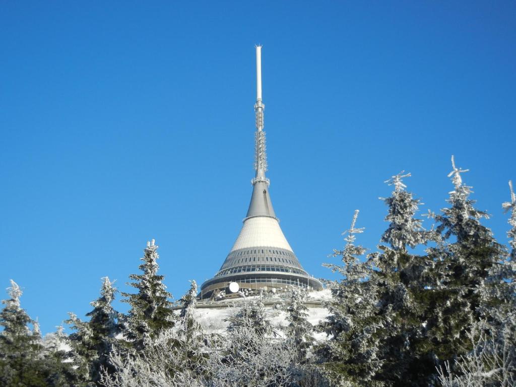 a steeple of a building with trees in the foreground at Hotel Ještěd in Liberec