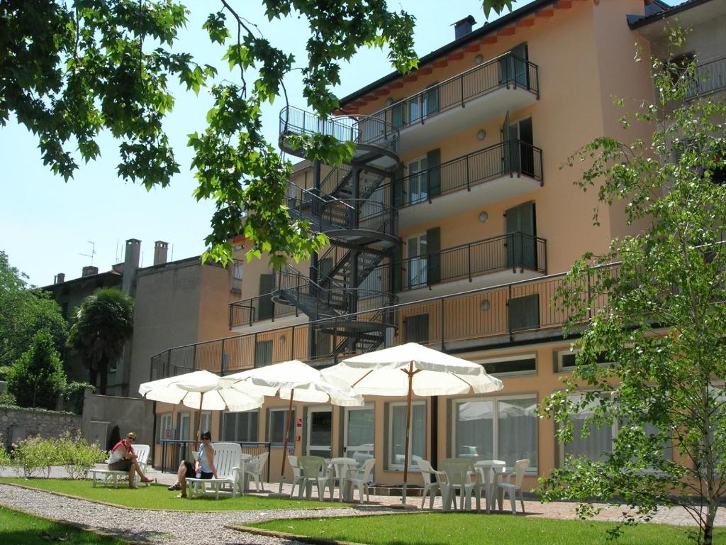 a building with tables and umbrellas in front of it at Ostello Città di Rovereto in Rovereto
