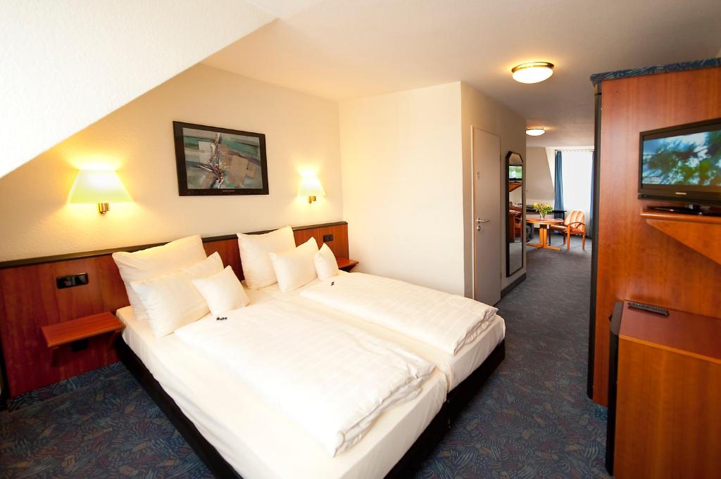 ein Hotelzimmer mit einem großen Bett und einem TV in der Unterkunft Advantage Appartements Hotel in Nürnberg