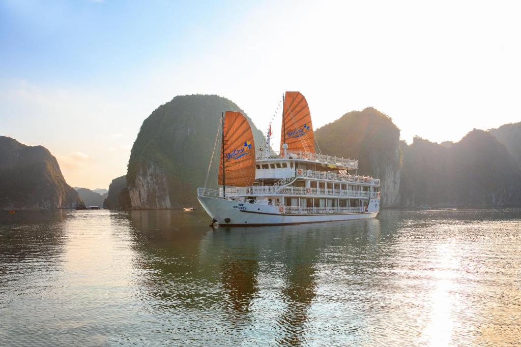 een cruiseschip met oranje zeilen in het water bij UniCharm Cruise in Ha Long