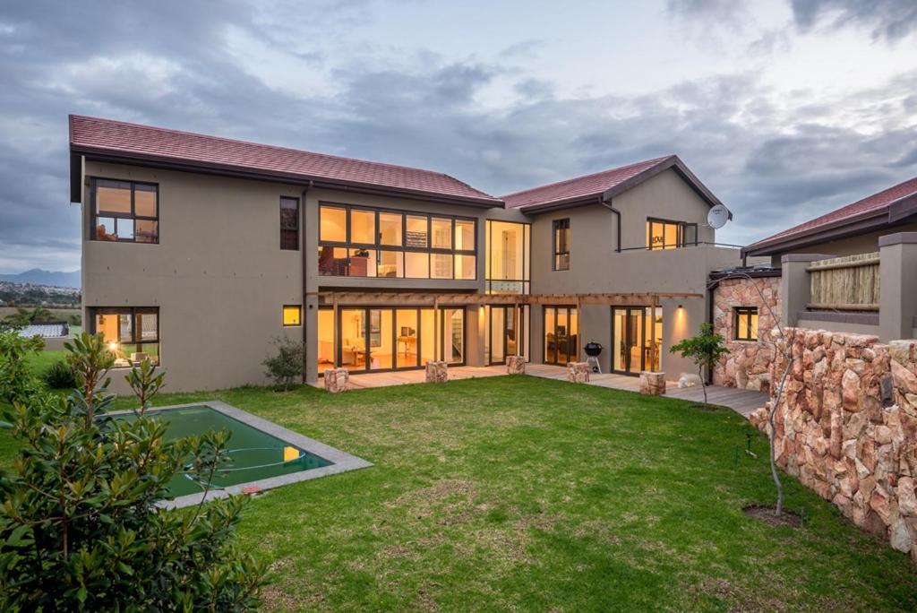 uma grande casa com um grande quintal com uma parede de pedra em Modern spacious home in heart of Cape Winelands em Somerset West