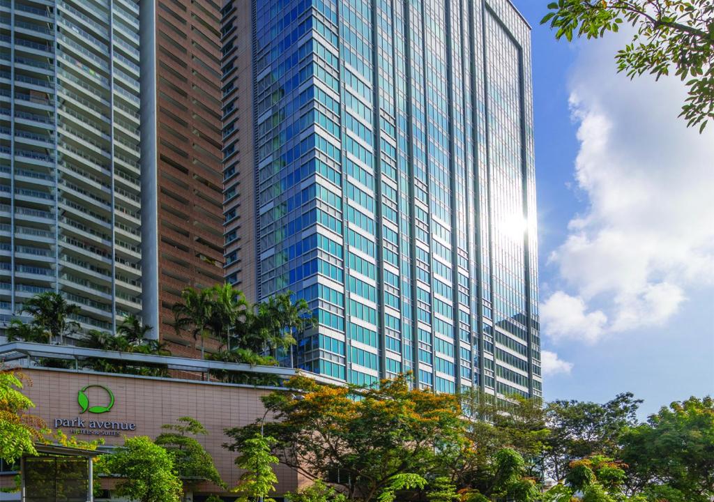 un grand bâtiment en verre avec des arbres devant lui dans l'établissement Park Avenue Rochester, à Singapour