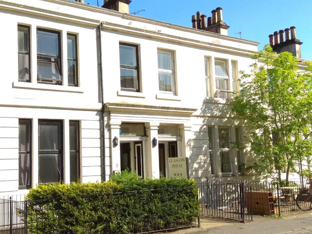 a white house with a sign in front of it at Glasgow House in Glasgow