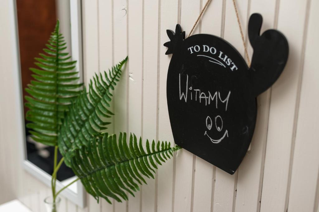 a black heart hanging on a wall next to a plant at K3Mhome in Wrocław