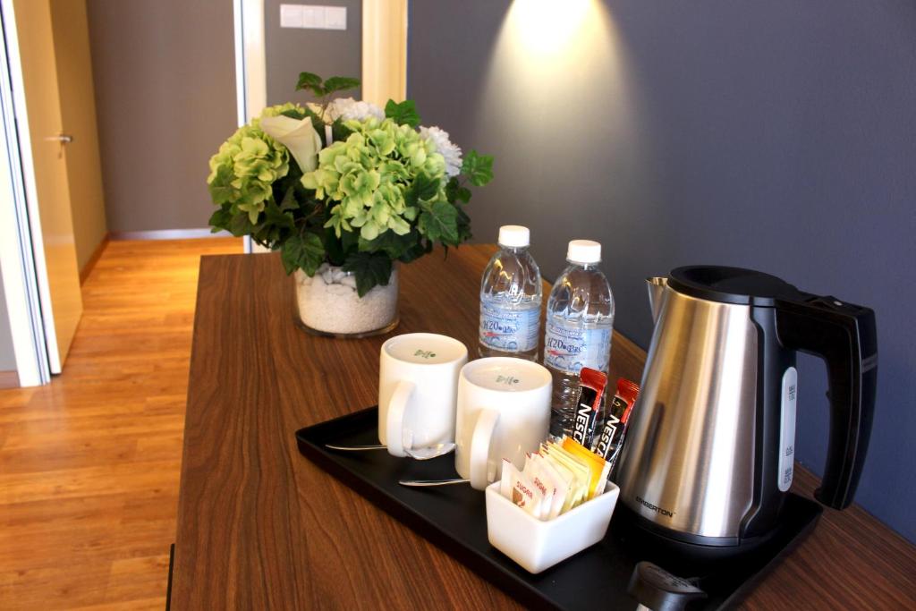 A hospitality tray offers a kettle, bottled water, cups and sachets on a wooden table.